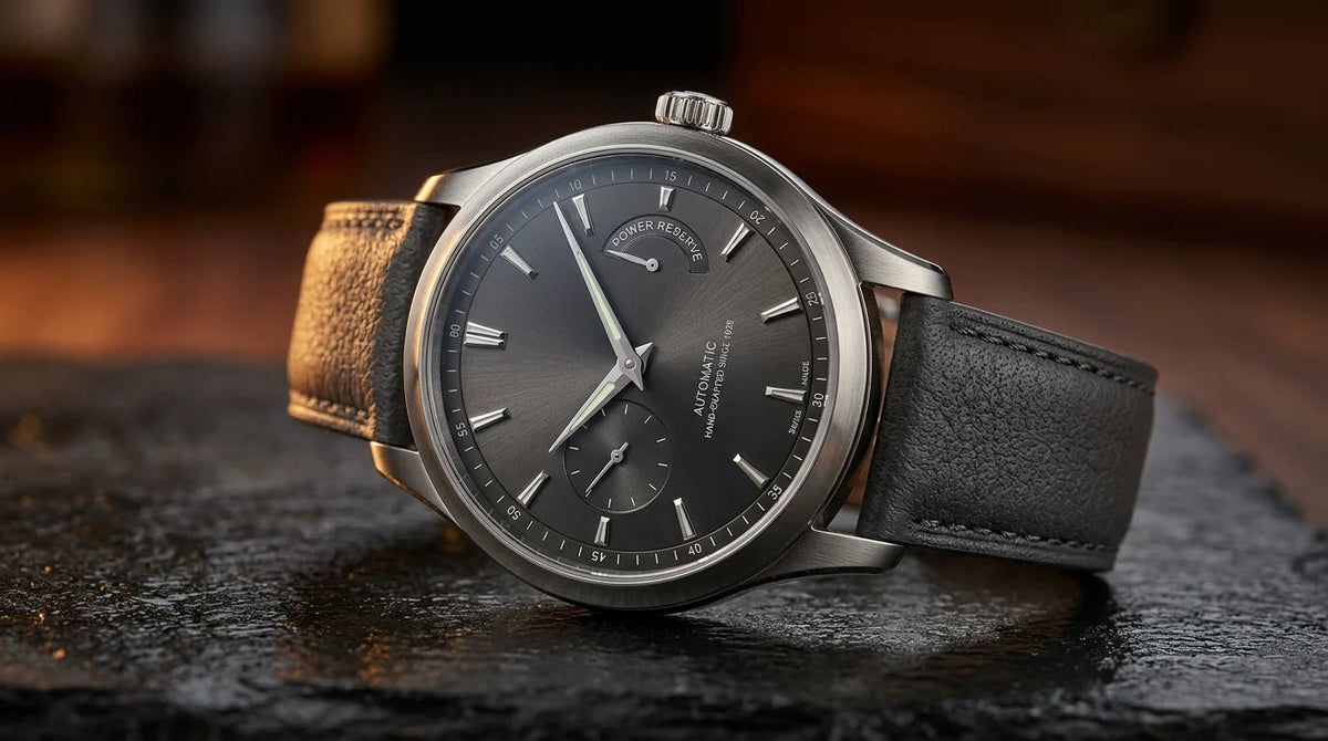 Refined mechanical luxury wristwatch on dark polished stone under warm lighting