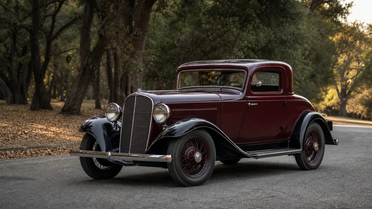 Historically styled 1934 American prewar coupe photographed on a quiet tree-lined road.