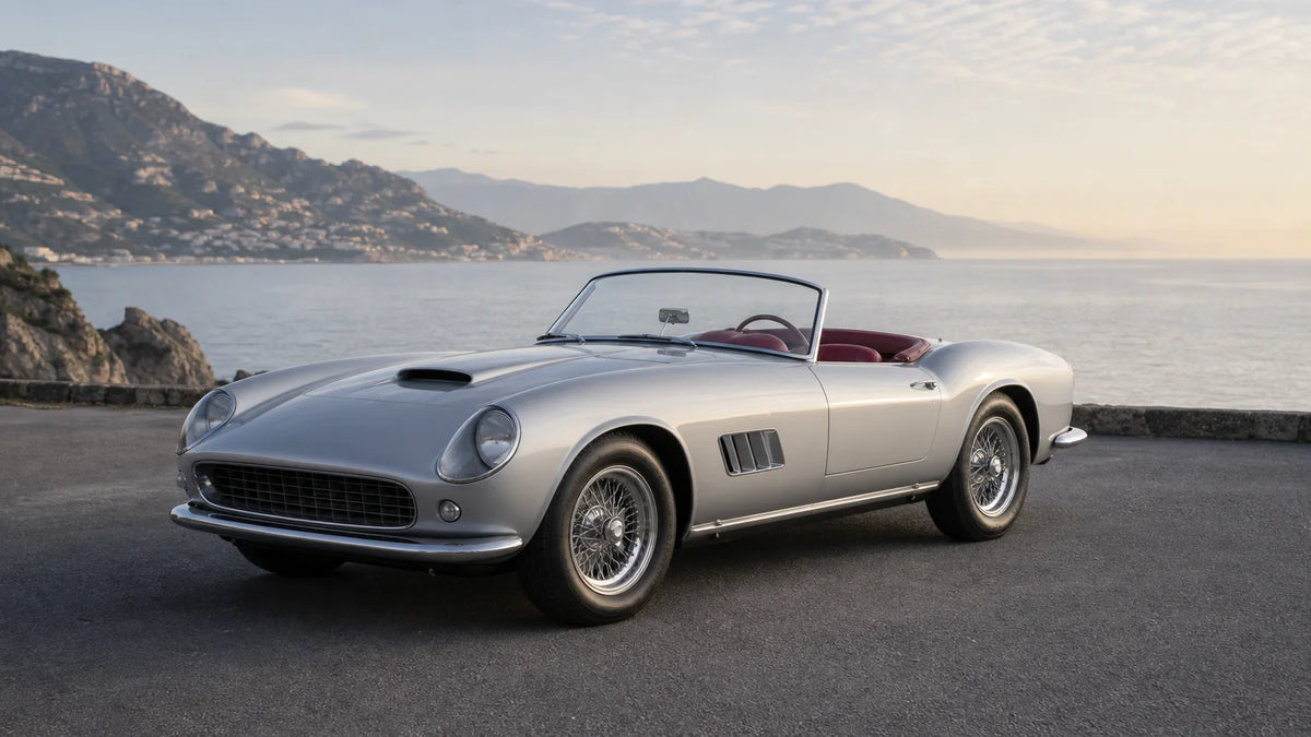 Silver 1963-style classic roadster on a quiet coastal road