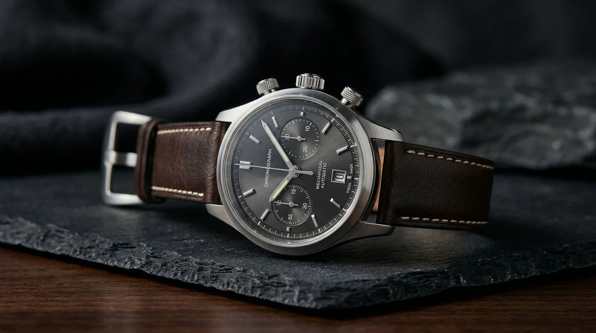 An elegant mechanical luxury wristwatch presented on a dark minimalist surface