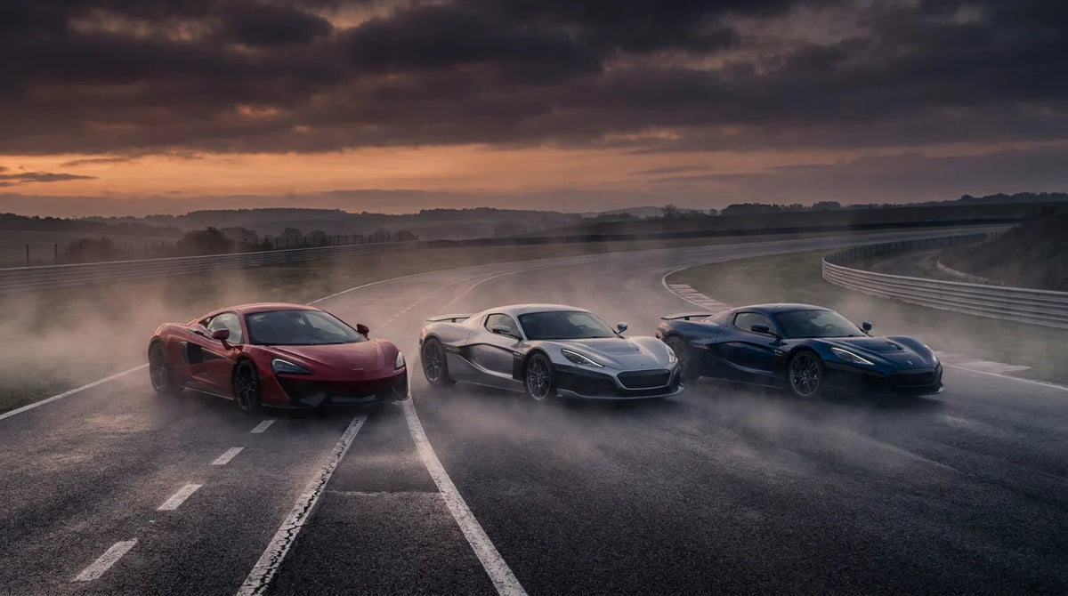 Three high-performance luxury sports cars lined up on a misty racetrack at dawn