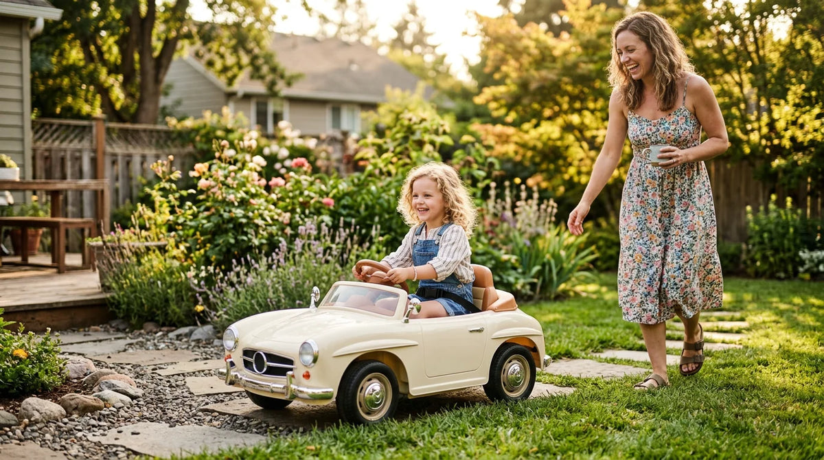 Young child driving an electric ride-on car in a sunlit backyard with a parent nearby